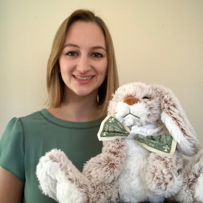 Charlotte Moller next to a stuffed animal bunny with a one dollar bill for a bow tie