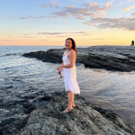 Grace Brangwynne standing on rocks at the beach