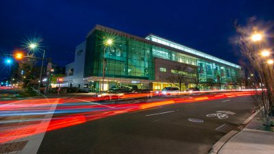 The UConn Stamford campus at night with car lights streaming past.